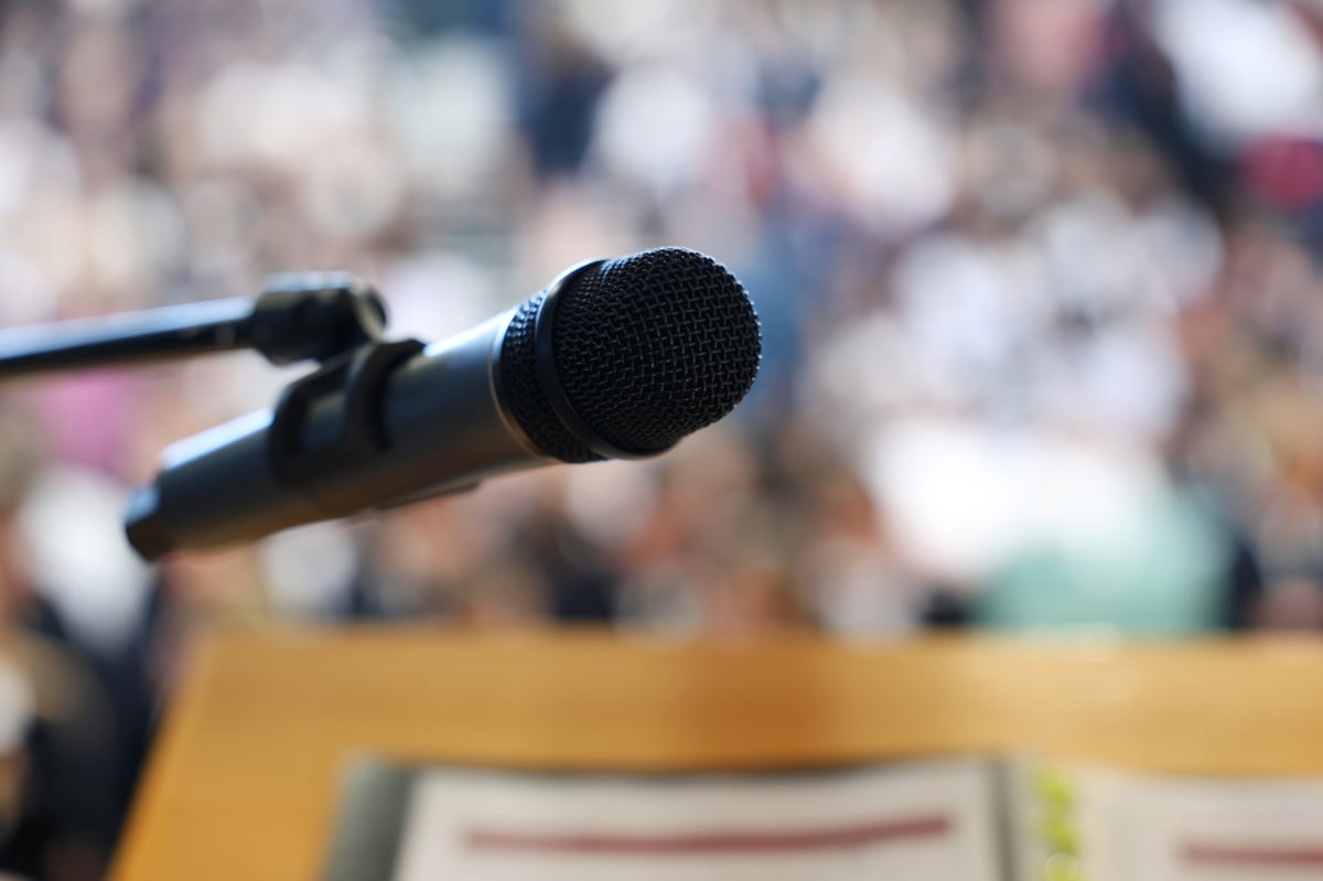 A microphone on a lectern in front of an attentive audience
