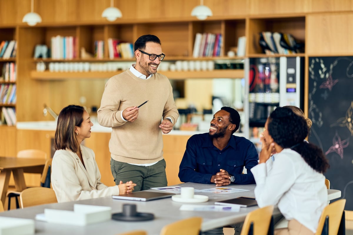 An instructor speaking with a diverse group of colleagues in a bright classroom